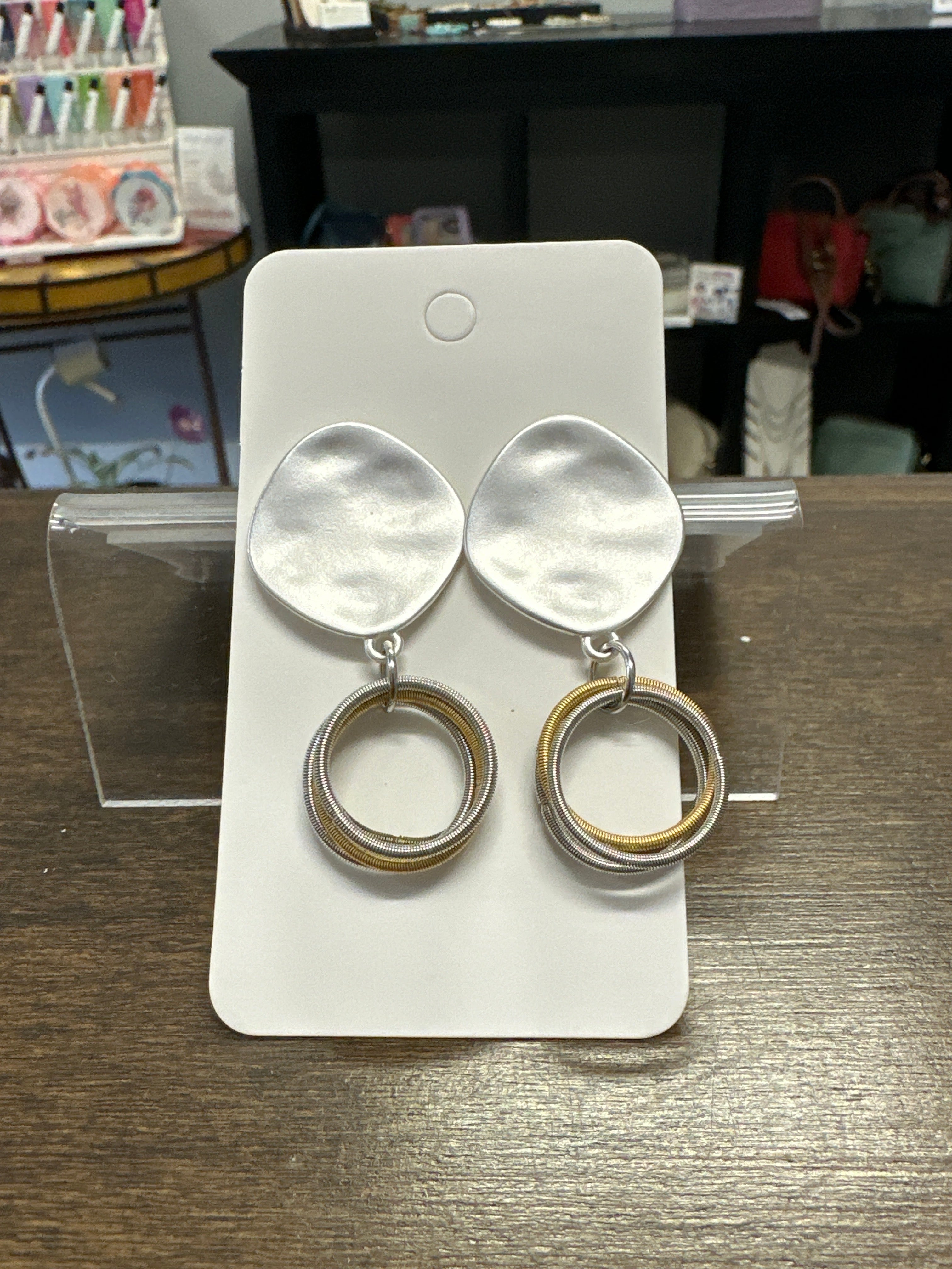 Pair of silver earrings on a white card with a blurred background