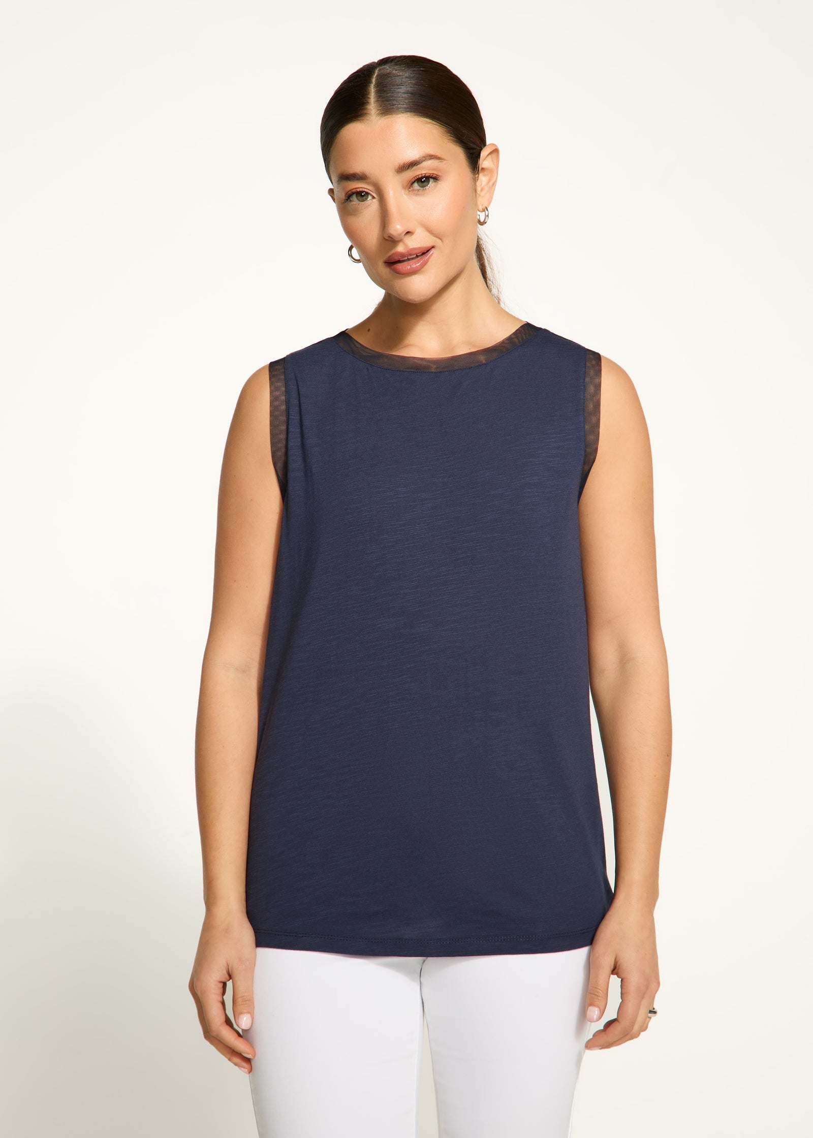 A woman wearing a navy sleeveless scoop neck top.