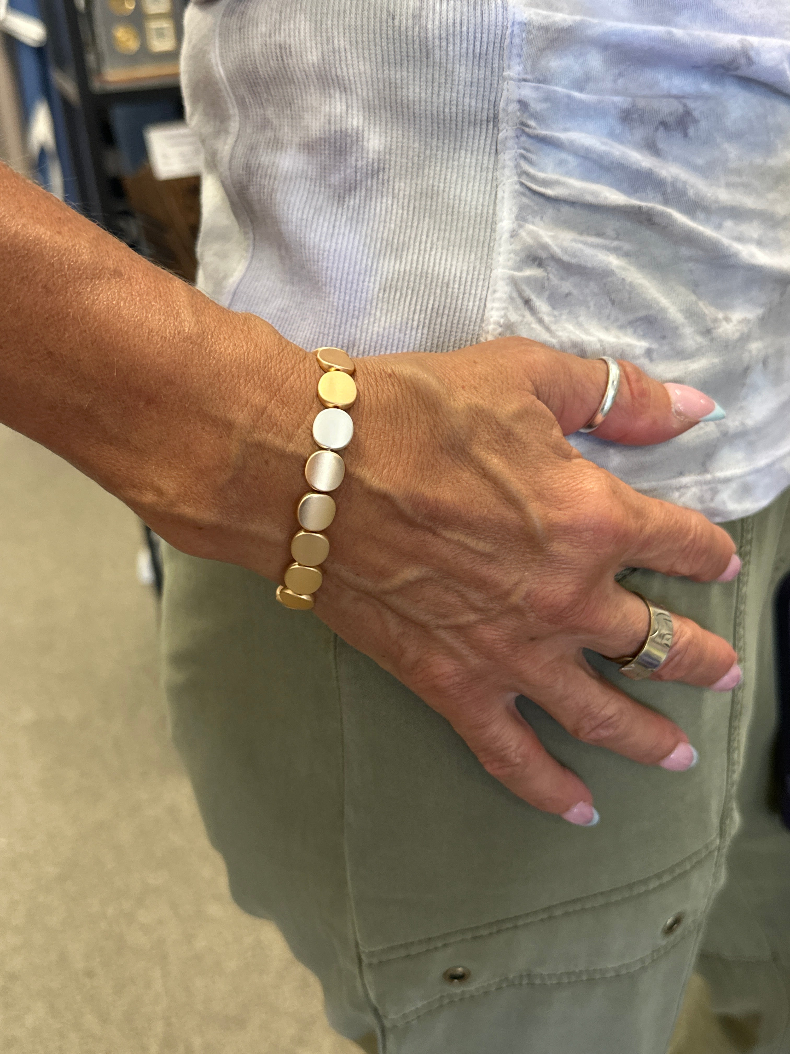 Hand wearing a gold bracelet with a blurred background