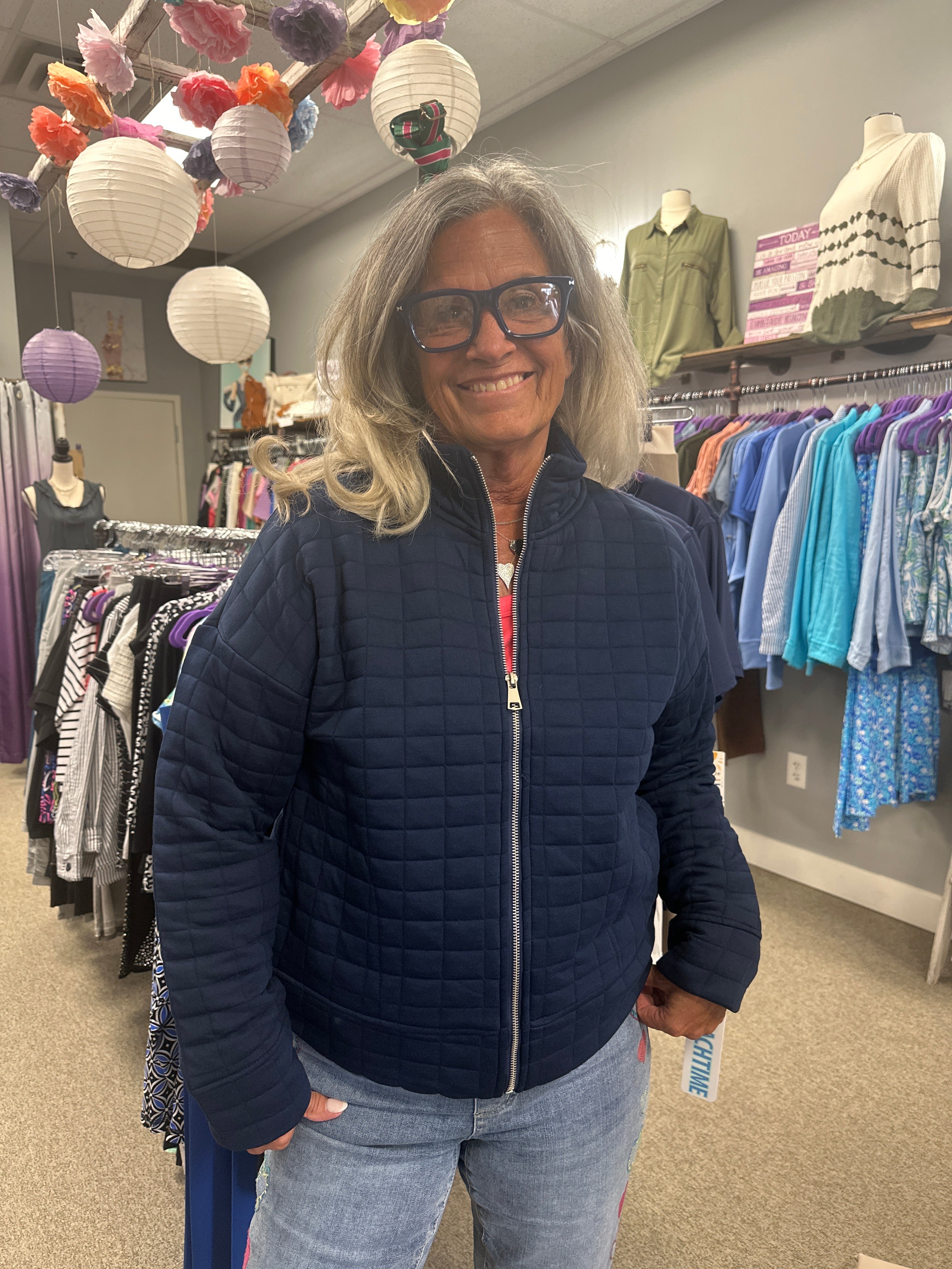 Person wearing a navy blue jacket in a store setting with fabric displays.
