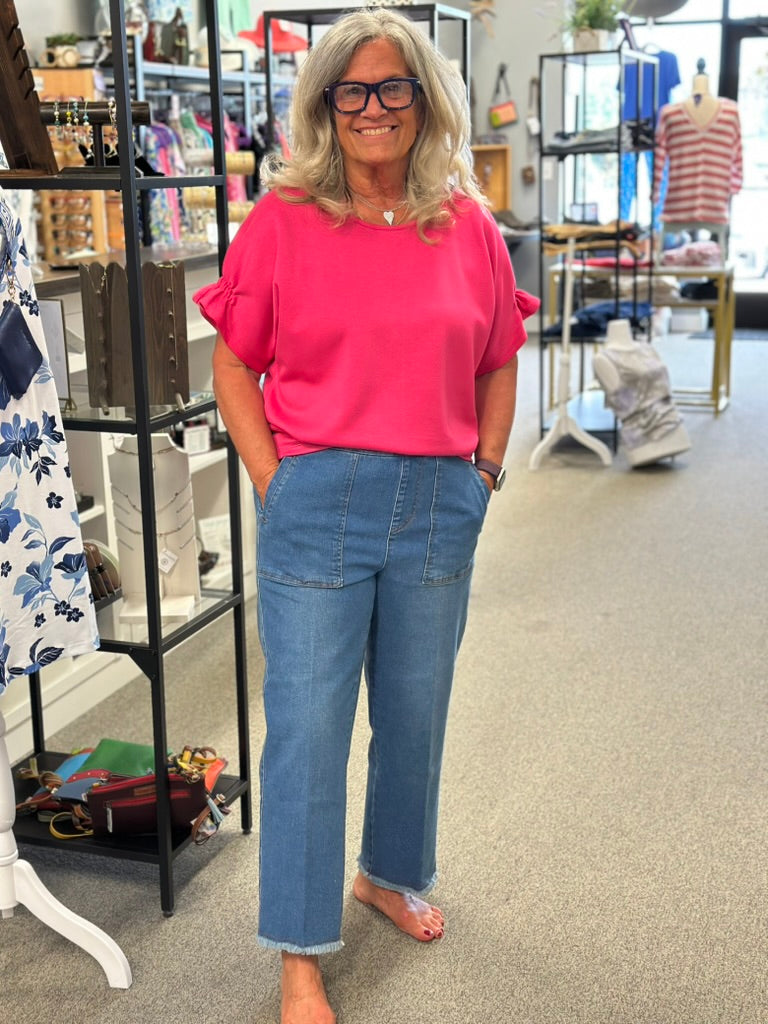 Woman wearing a pink blouse and blue jeans standing in a store.