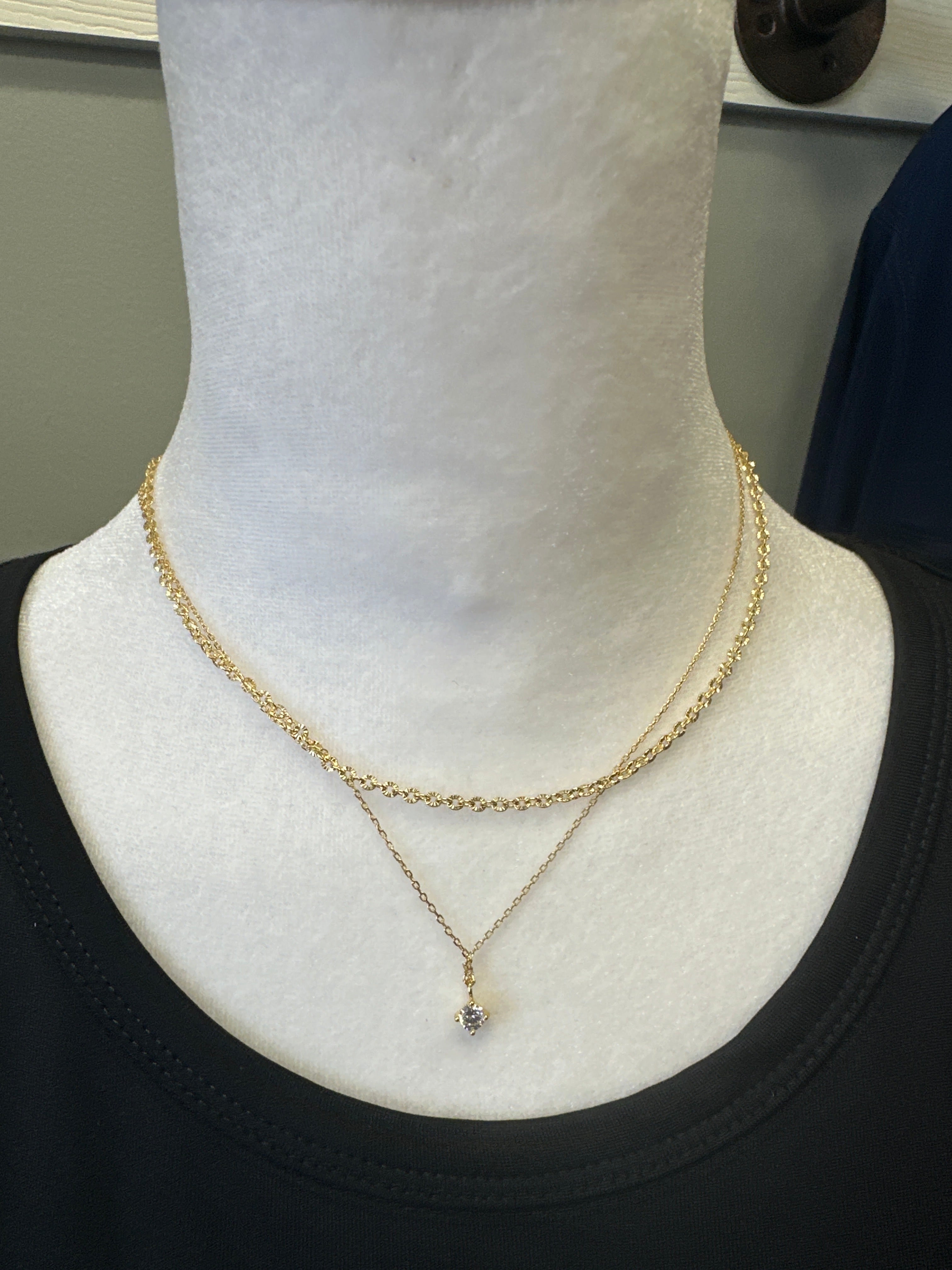 Gold necklace on a white stand with a blurred background