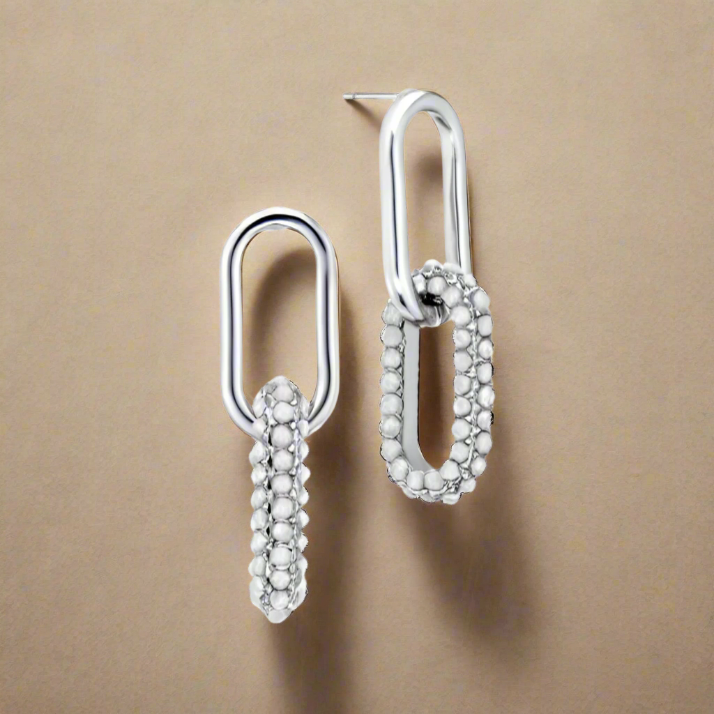 Pair of silver earrings on a beige background
